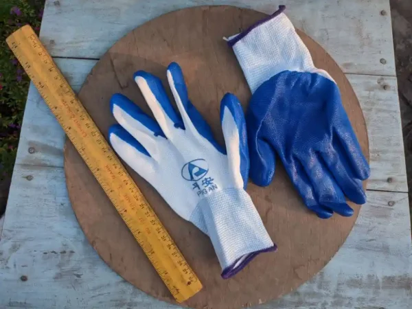 Blue and white nylon gardening gloves displayed on a wooden surface alongside a measuring ruler, ideal for hand protection during gardening tasks in Bangladesh